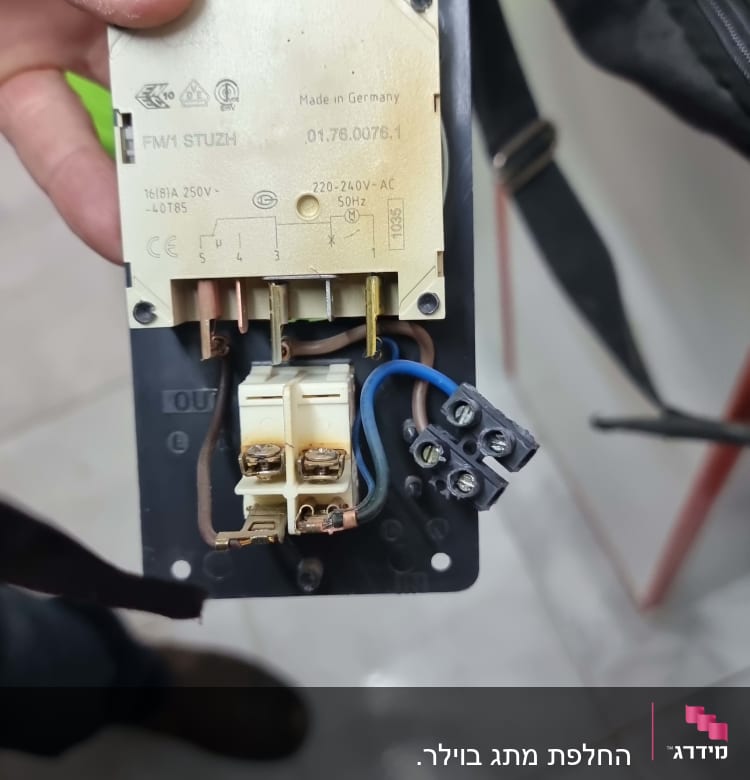 חלק חשמלי עם חיבורים וכיתוב על לוח מתכת